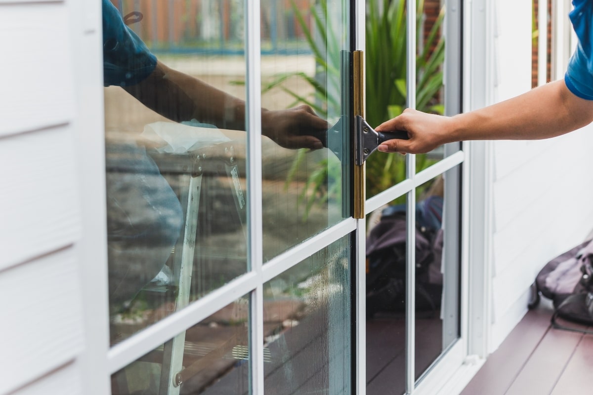 Maintaining a clean tinted window – A person gently cleaning a window with a squeegee, highlighting the importance of regular maintenance for preserving the clarity of tinted glass.