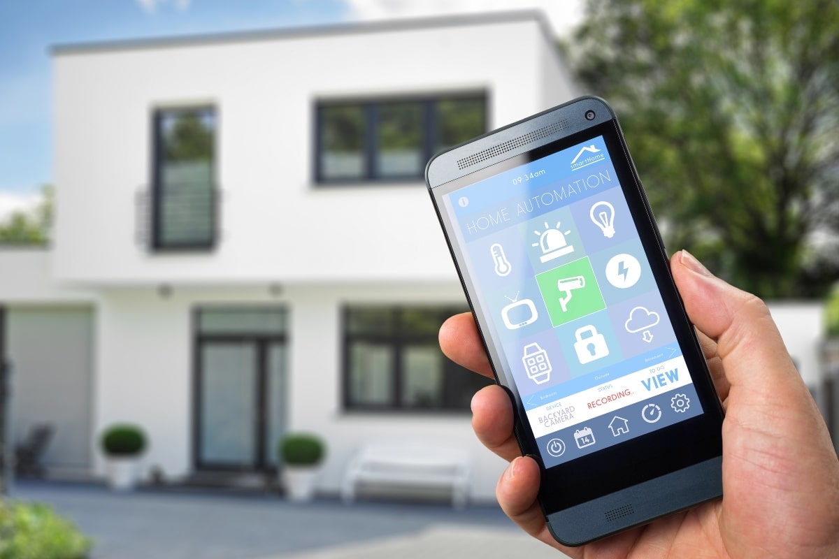 A person holding a smartphone displaying a home automation security app.