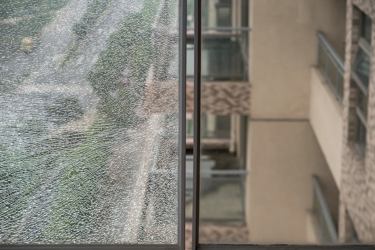 Comparison of shattered and undamaged window panes – A window featuring one side that is shattered and another that remains intact, highlighting how window film can prevent glass from shattering into dangerous shards.